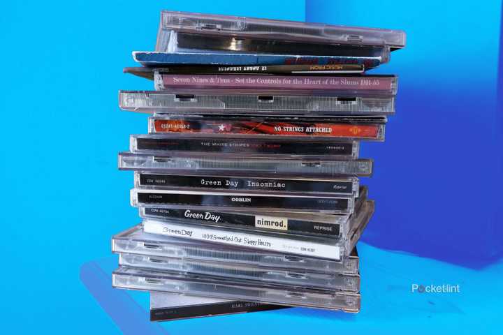 A stack of CDs in cases on a wooden desk