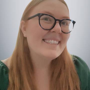 
Photo of white woman with glasses and red hair smiling at camera
