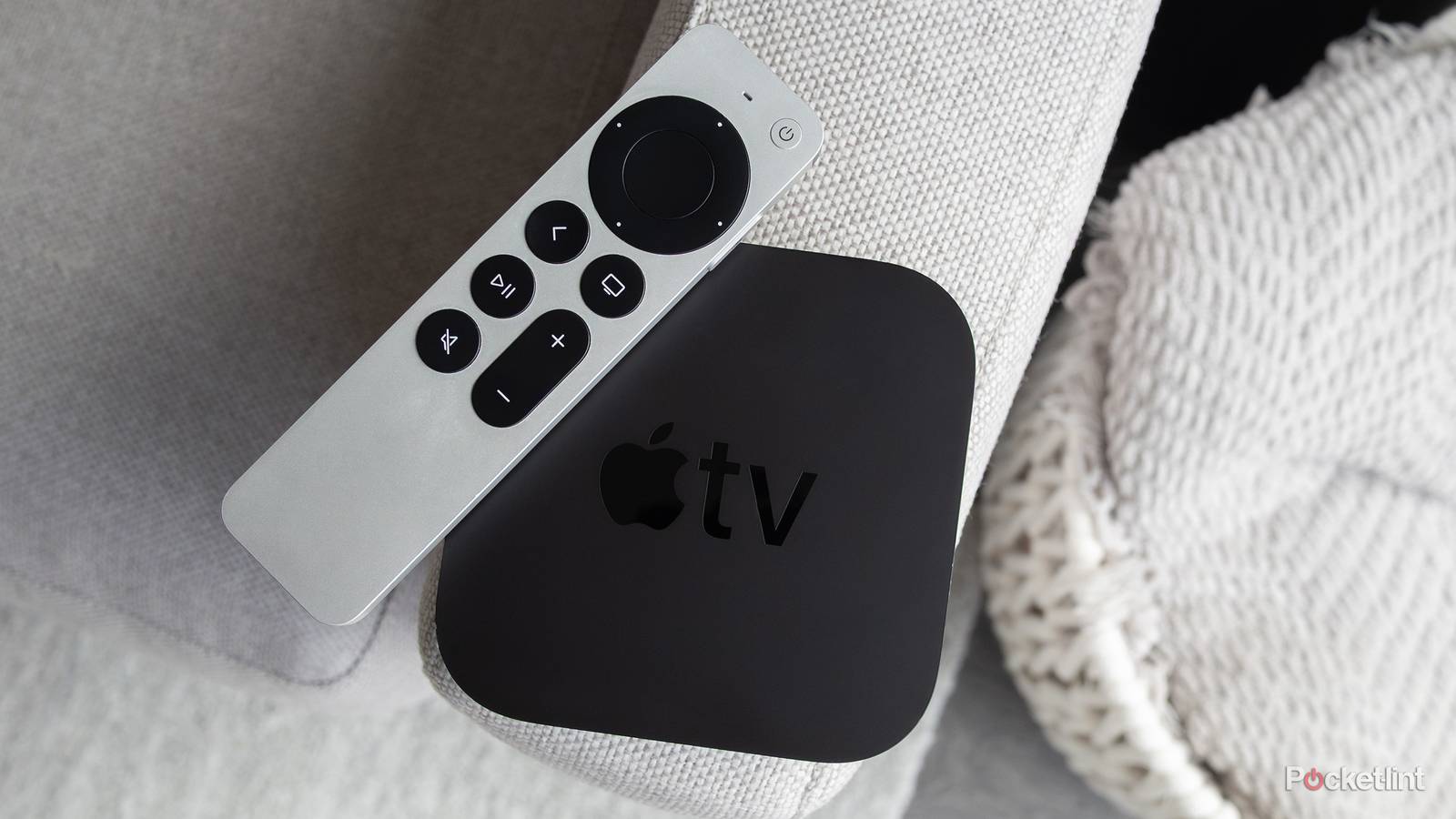 The Apple TV 4K and the Siri Remote sitting on a couch arm