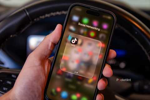 A still photo of a driver holding their phone with the TikTok app displayed. 