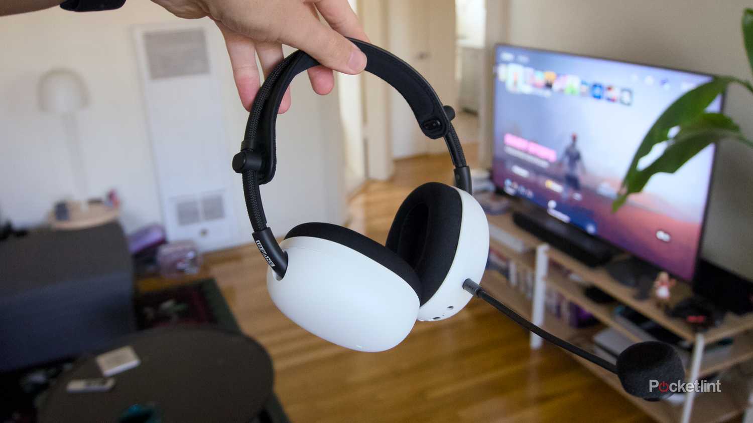 A hand holding white InZone H9 II wireless headphones.