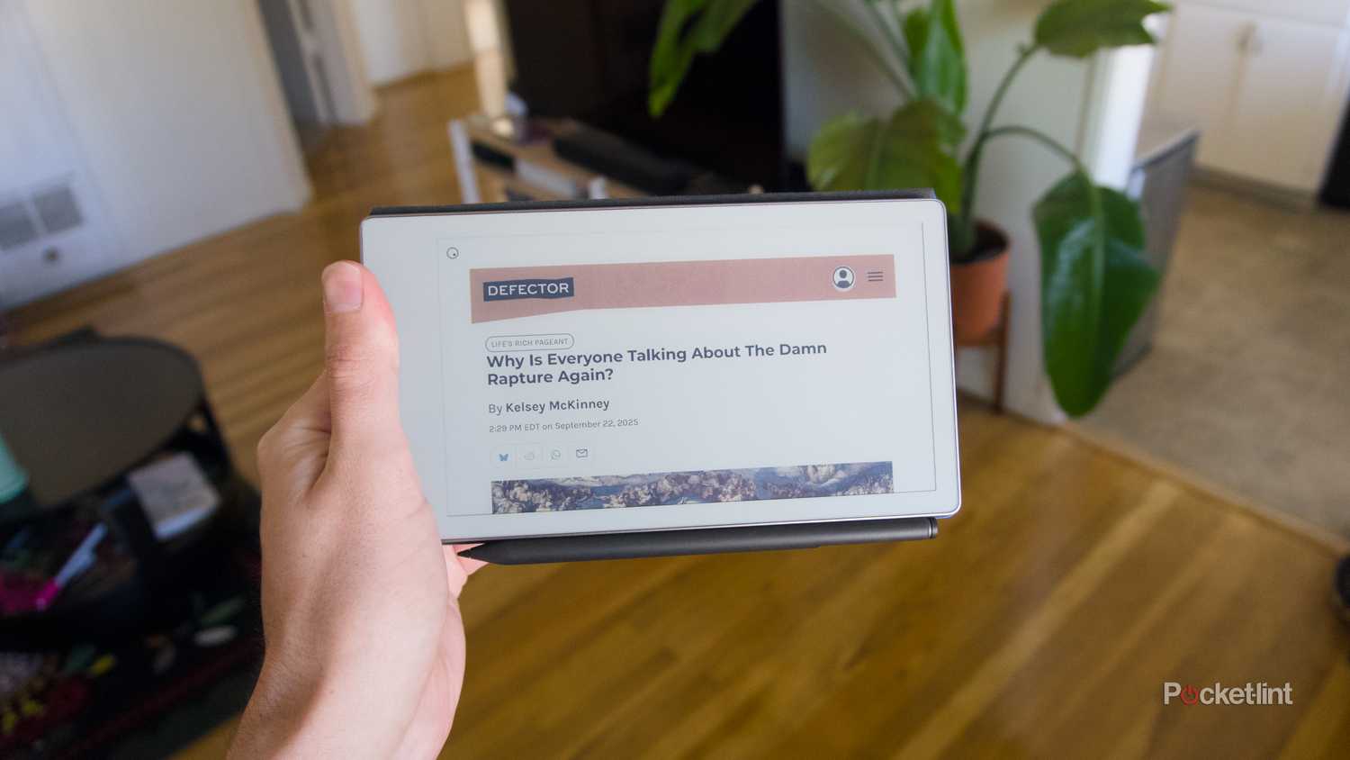 A hand holding a reMarkable Paper Pro Move in landscape orientation with an article open.