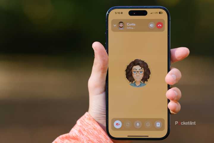 A hand holds an iPhone with a Snapchat video call.
