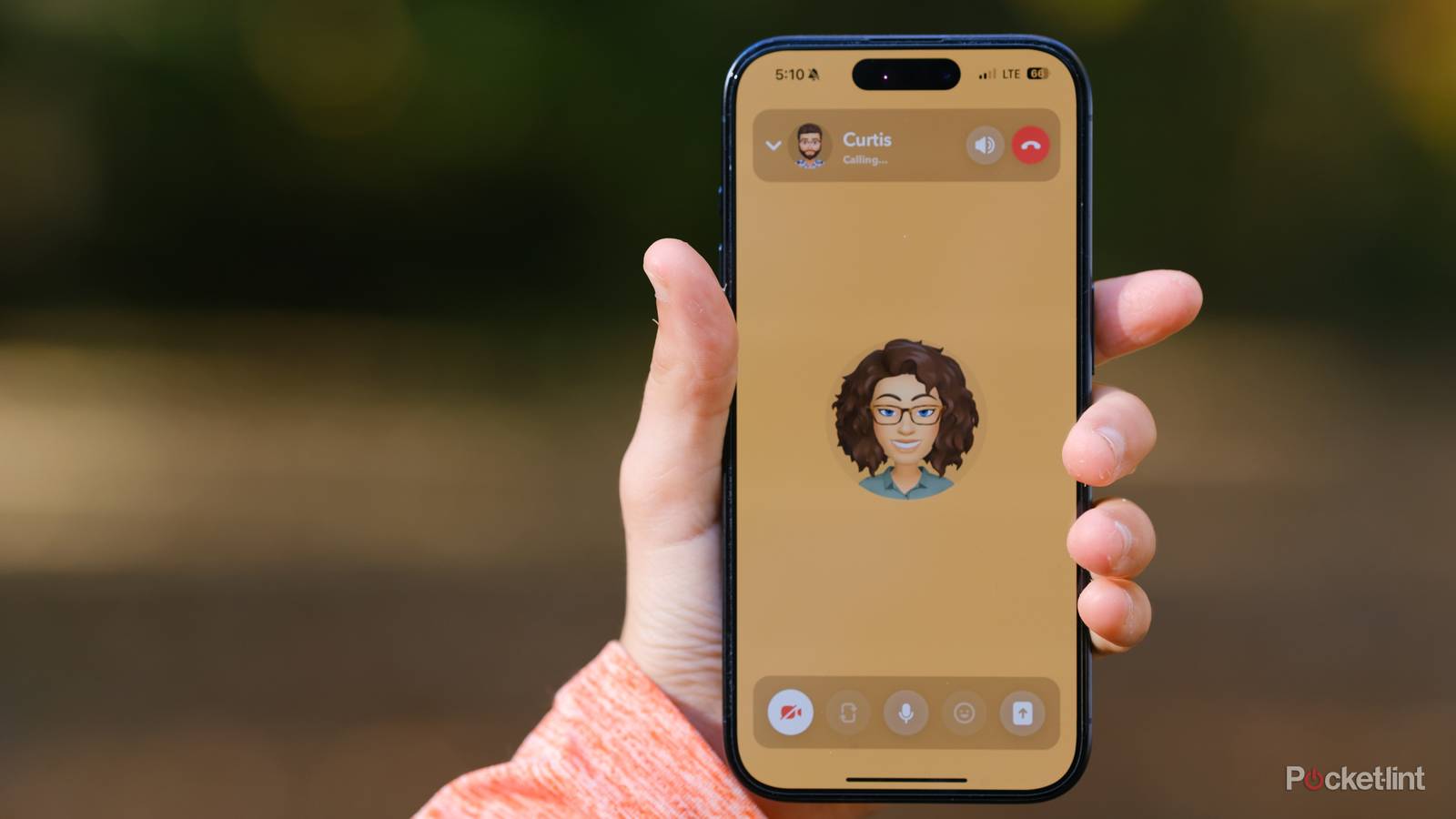 A hand holds an iPhone with a Snapchat video call.