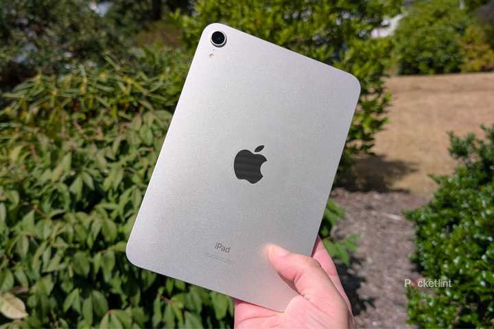An iPad mini being held up in the air.