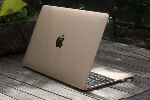 A gold 12-inch MacBook outside on a wooden table.