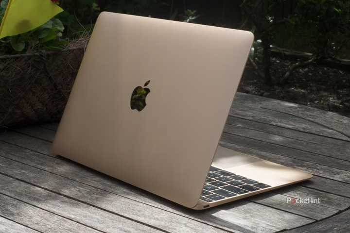 A gold 12-inch MacBook outside on a wooden table.