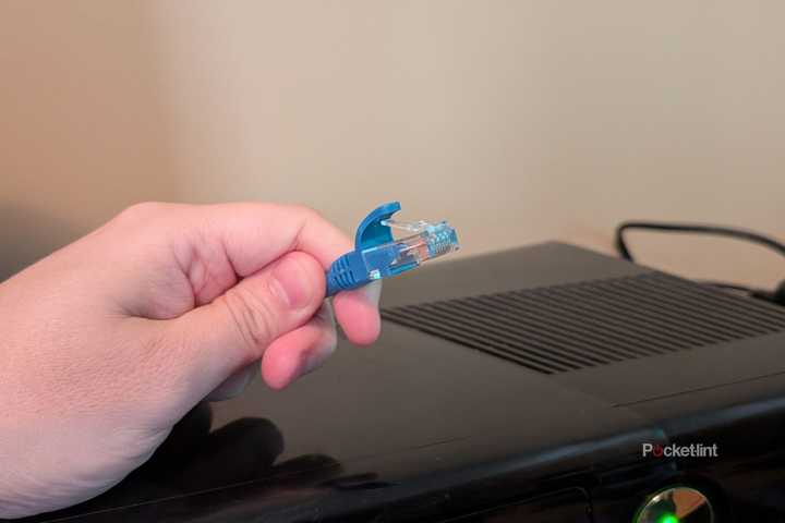 A person holding an Ethernet cable over an Xbox 360.