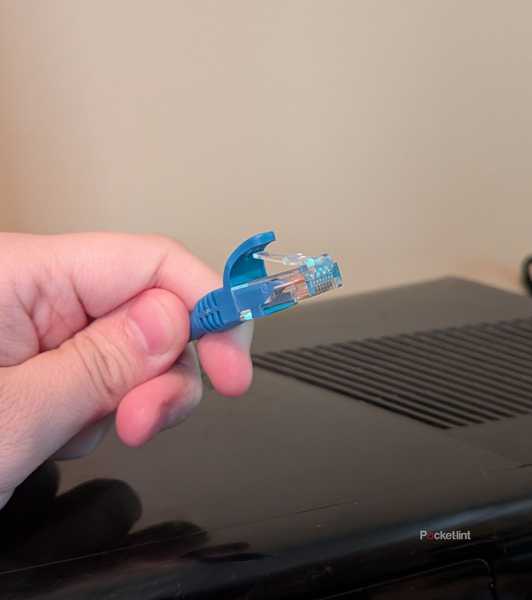 A person holding an Ethernet cable over an Xbox 360.