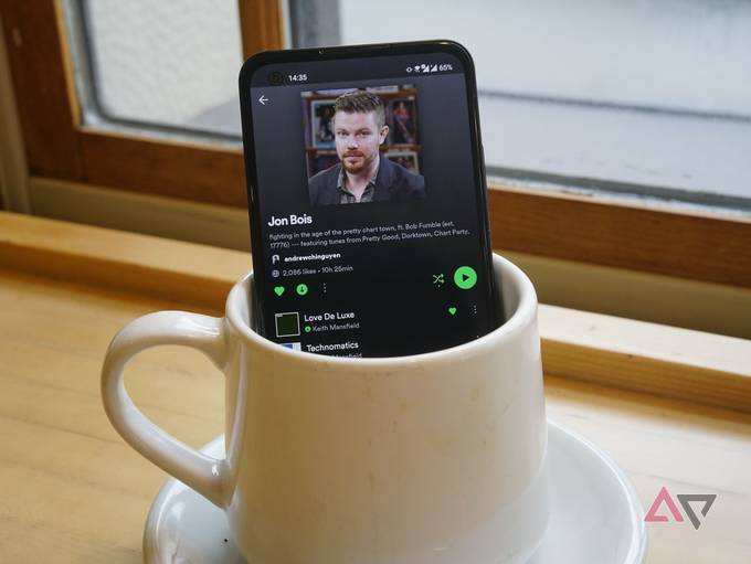 spotify on the scren of a phone that is stiting in a coffee cup