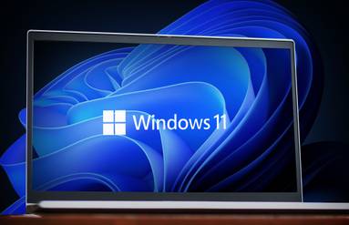 Laptop screen displaying Windows 11 logo with a blue abstract background.