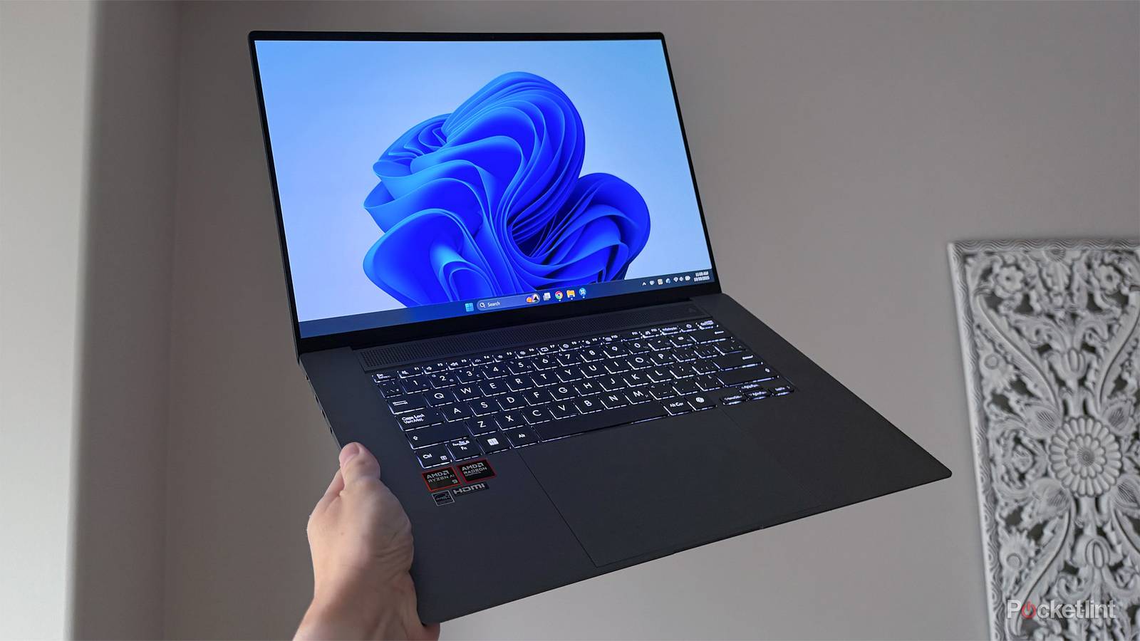 A Windows 11 laptop being held up in the air.