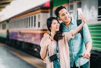 couple taking a selfie beside a train - yesim