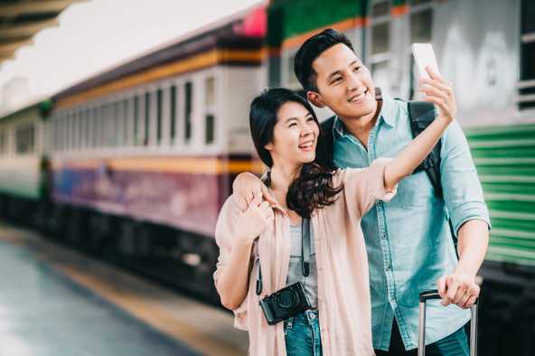 couple taking a selfie beside a train - yesim