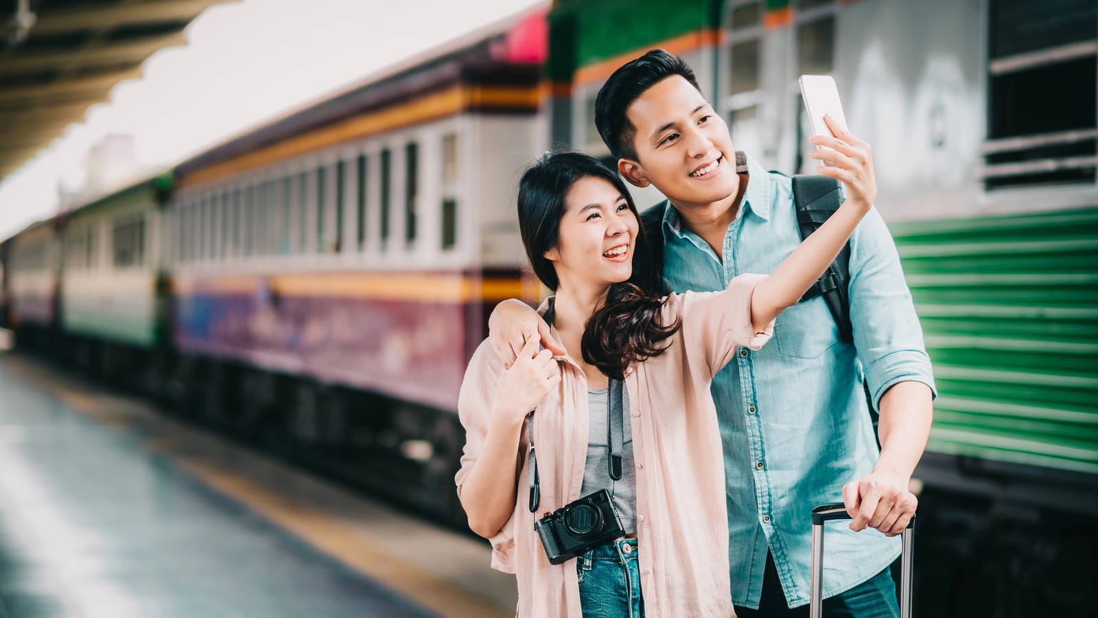 couple taking a selfie beside a train - yesim